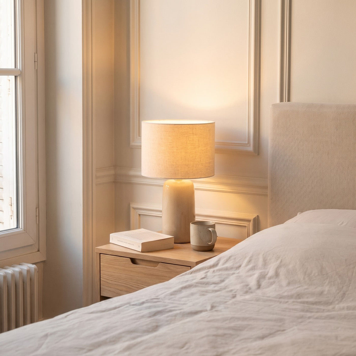 Lampe de chevet allumee sur une table de chevet en bois clair Image