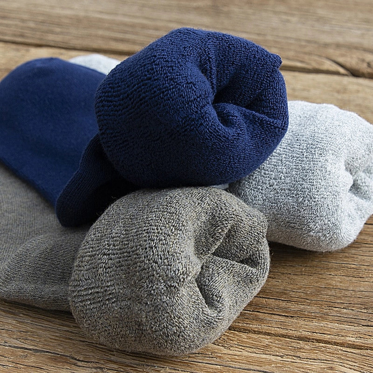 Cinq coloris de chaussettes hautes roulées sur une table en bois