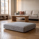 Coussin de sol carré gris clair posé sur le parquet d'un salon