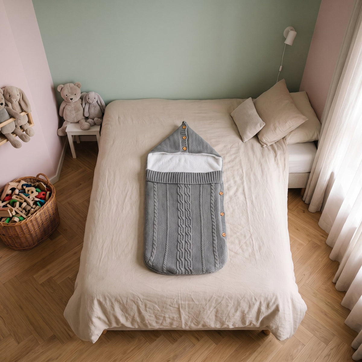 Gigoteuse bébé en tricot gris posée sur un lit d'enfant