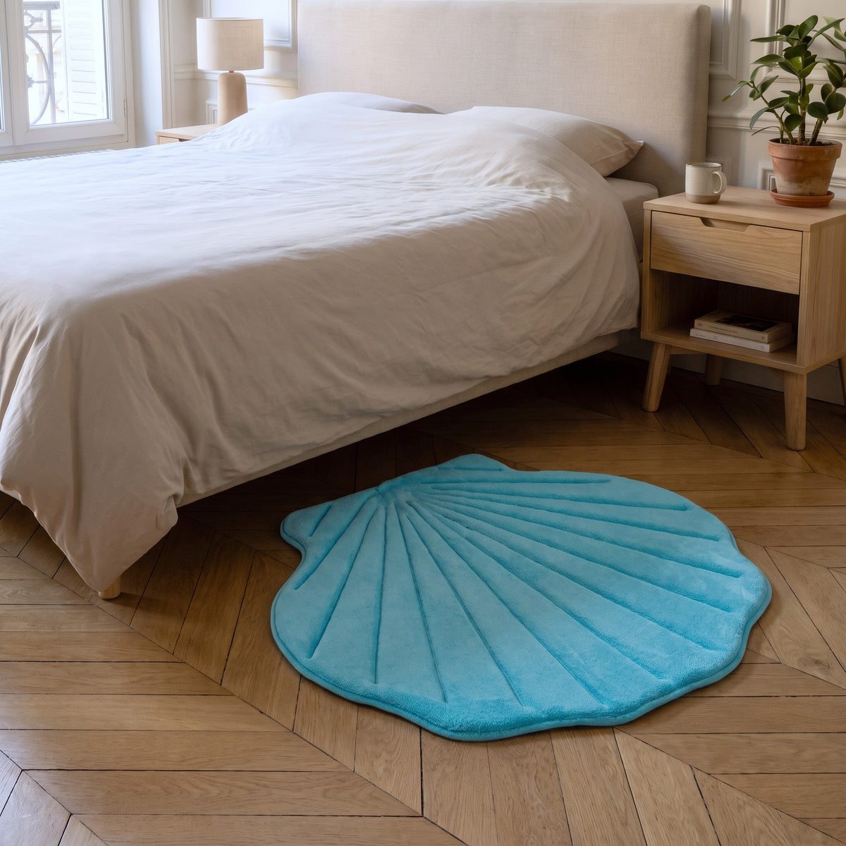 Tapis coquillage bleu turquoise posé au pied d'un lit sur un parquet en point de Hongrie