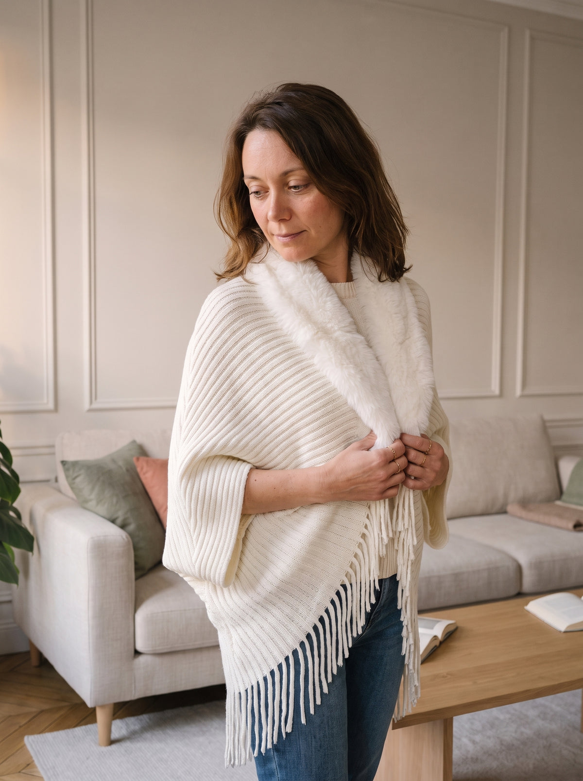 Femme du casting portant le poncho blanc en maille dans le salon