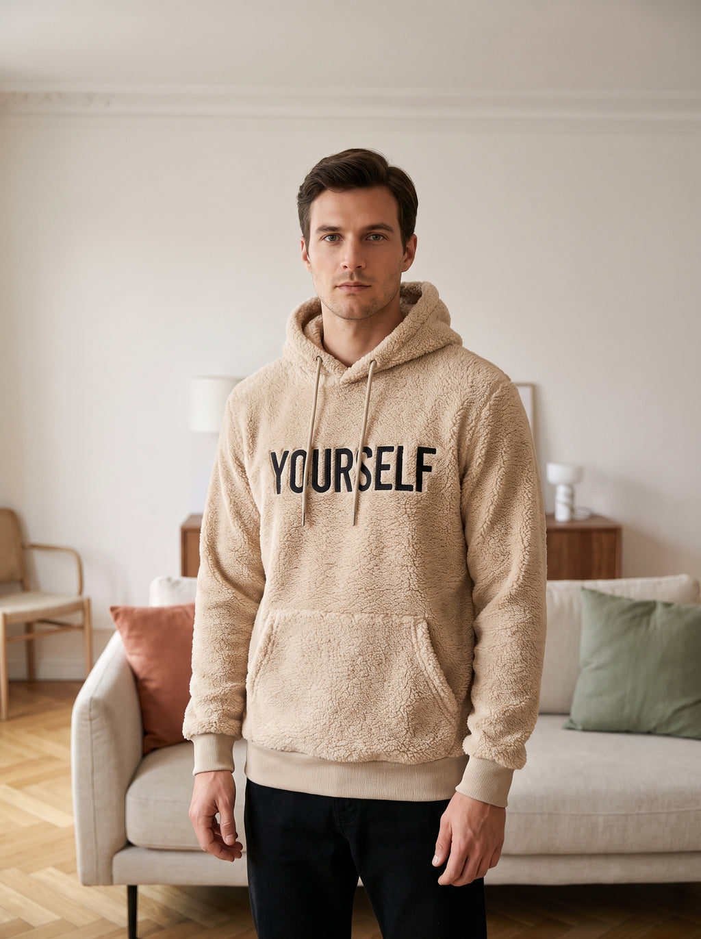 Homme portant le sweat à capuche peluche YOURSELF beige dans un salon