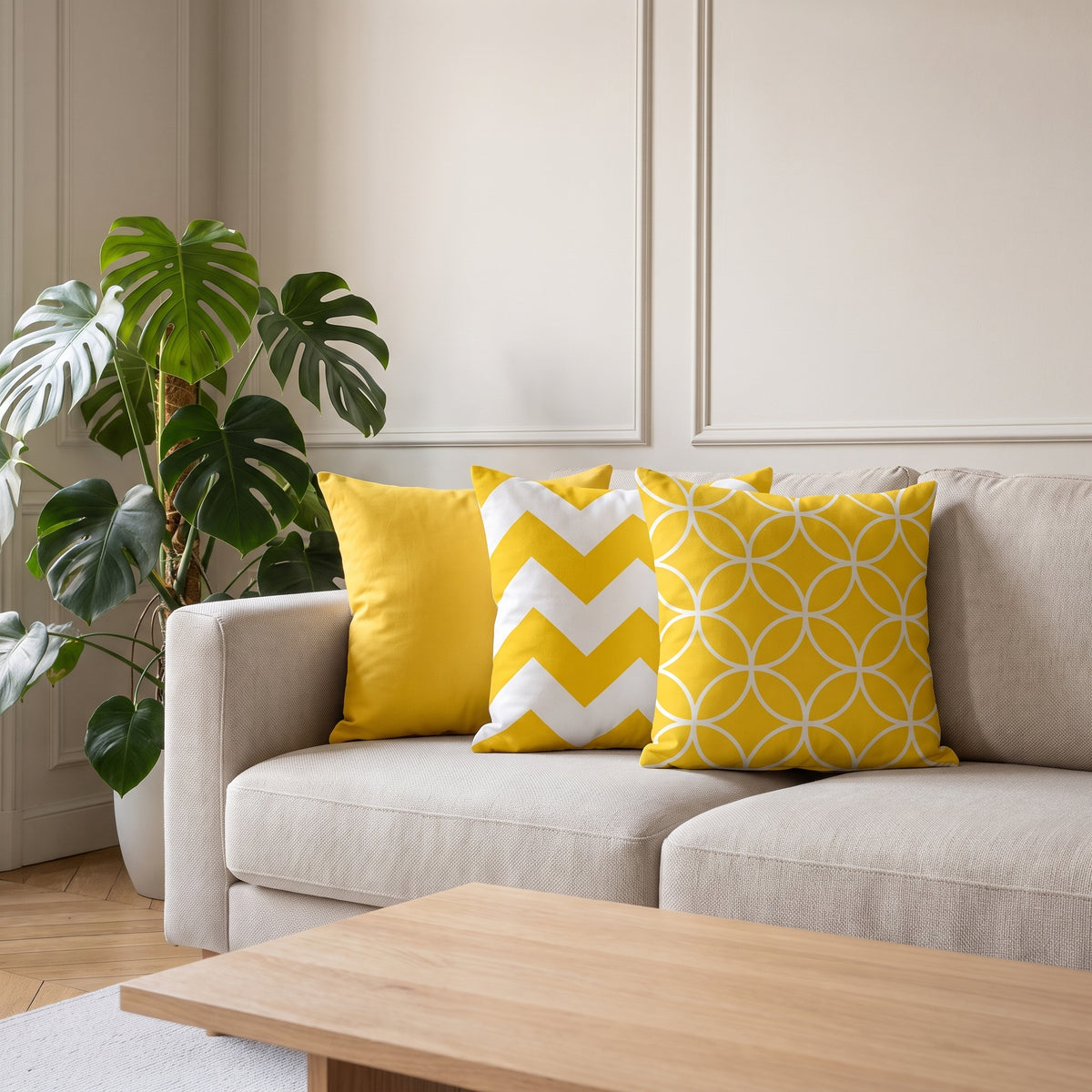 Trois housses de coussin jaunes, unie, à chevrons et à cercles entrelacés, posées sur un canapé écru dans un salon haussmannien