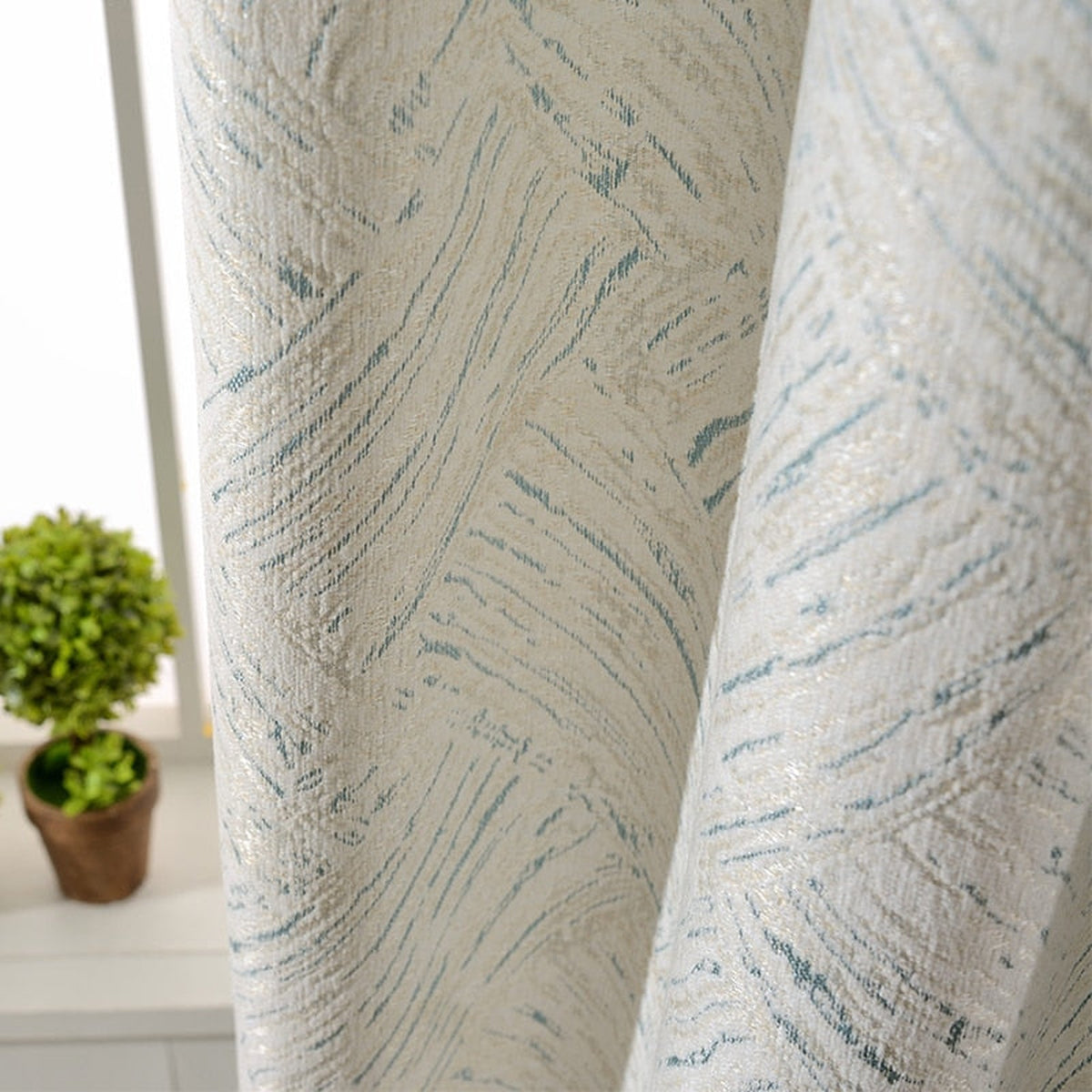 Gros plan sur la texture écrue et les fines touches bleutées du rideau en chenille
