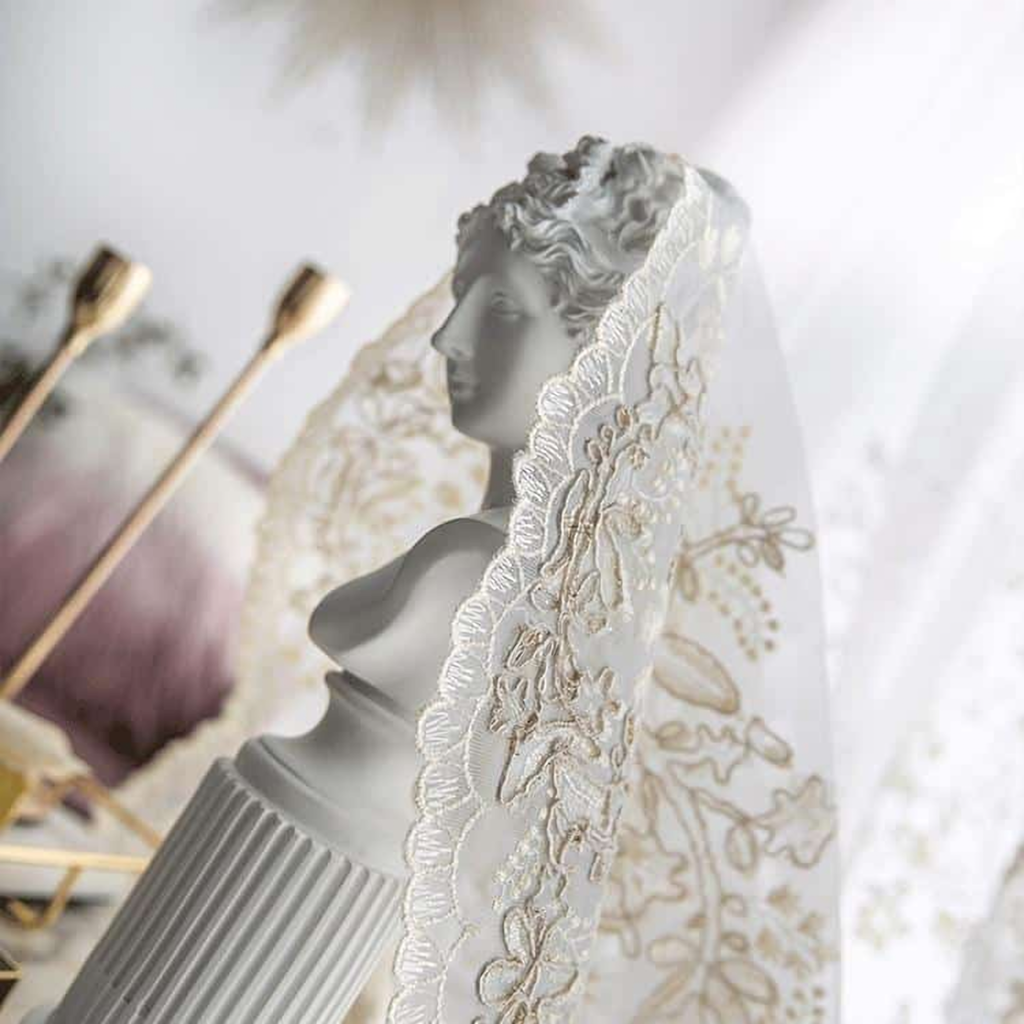 Voilage en dentelle fleurie drapé sur un buste en plâtre, lumière naturelle