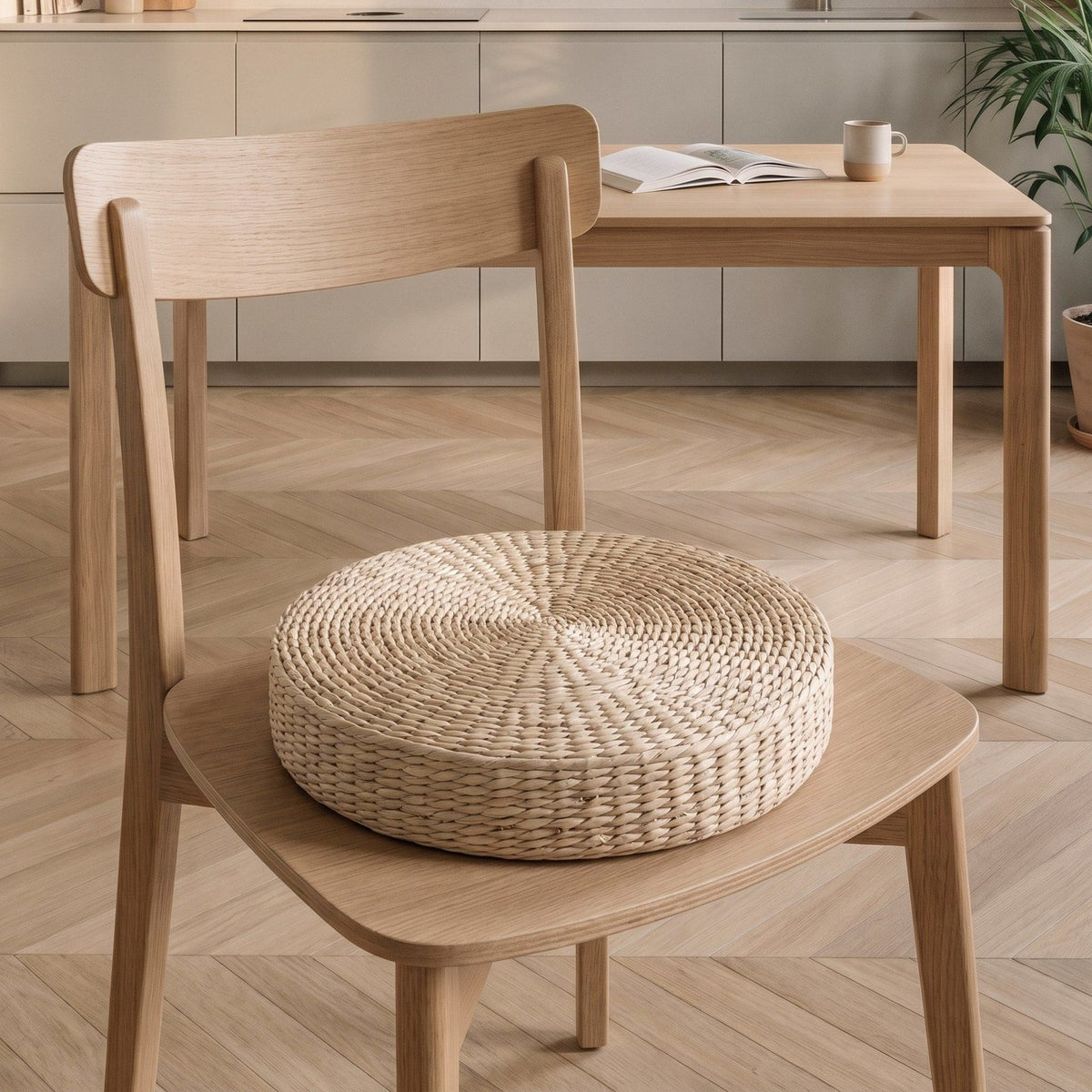 Coussin de sol en paille posé sur l'assise d'une chaise en bois clair