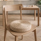 Coussin de sol en paille posé sur l'assise d'une chaise en bois clair