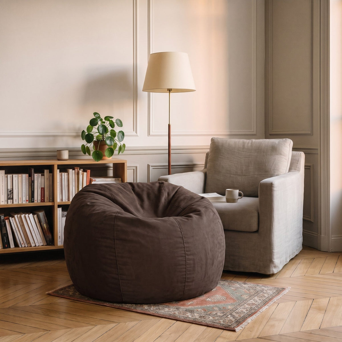 Pouf géant chocolat en microfibre posé dans un coin lecture, à côté d'un fauteuil