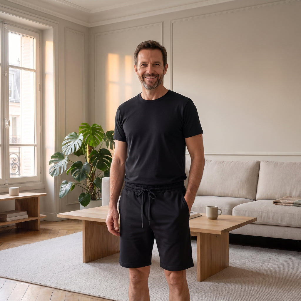 Ensemble d'été homme noir, t-shirt à col rond et short, porté dans un salon