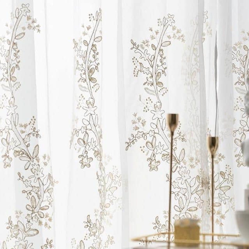 Détail de la broderie florale beige sur le voile blanc