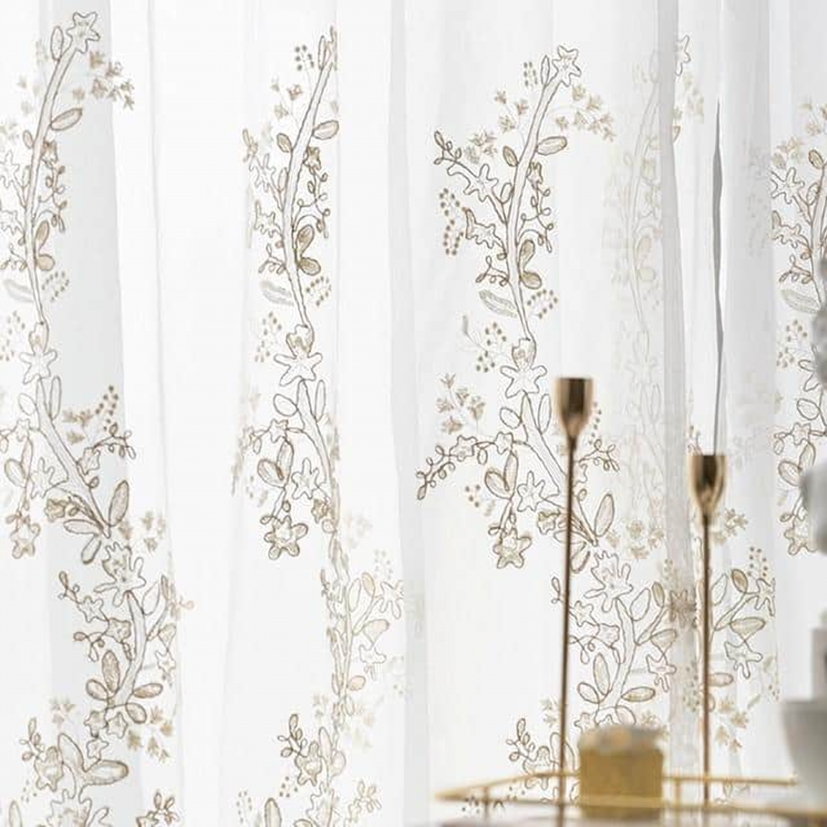 Détail de la broderie florale beige sur le voile blanc