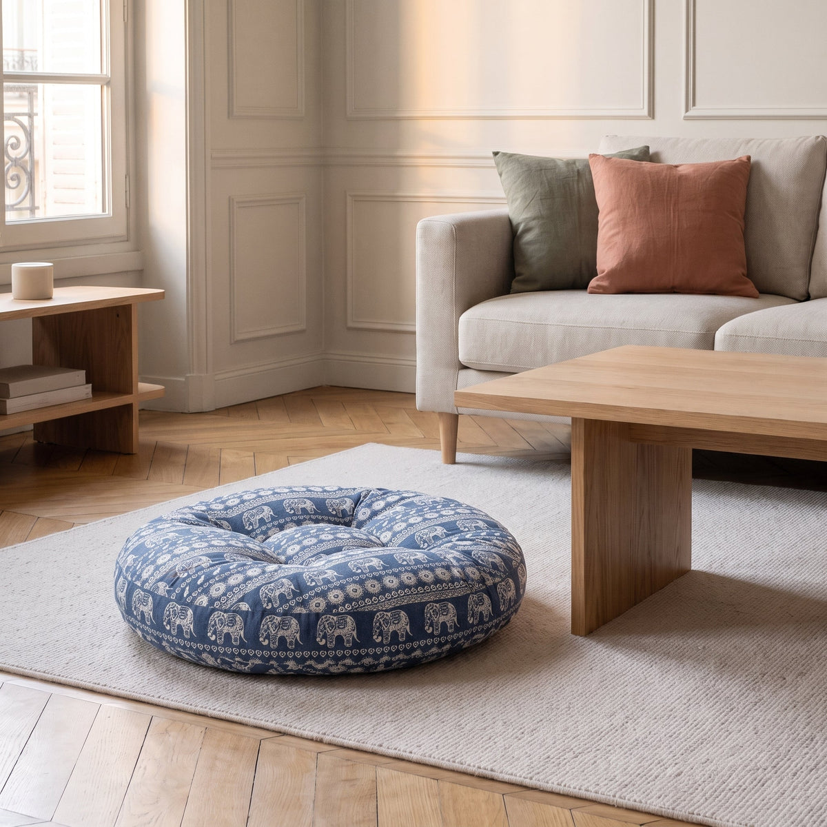 Coussin de sol rond imprimé éléphants blancs sur fond bleu jean, posé au sol dans un salon