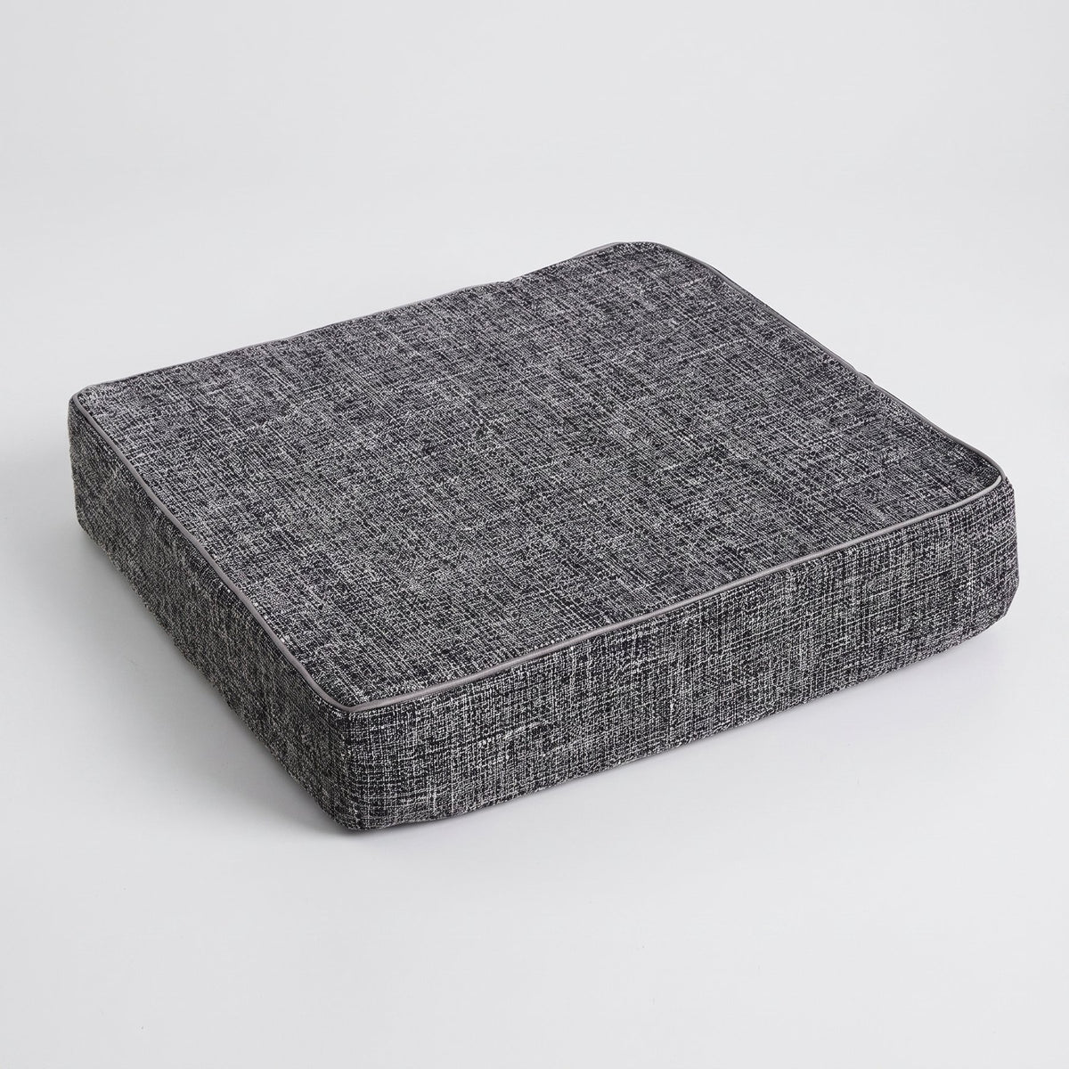 Coussin de sol gris foncé vu de trois quarts sur fond clair