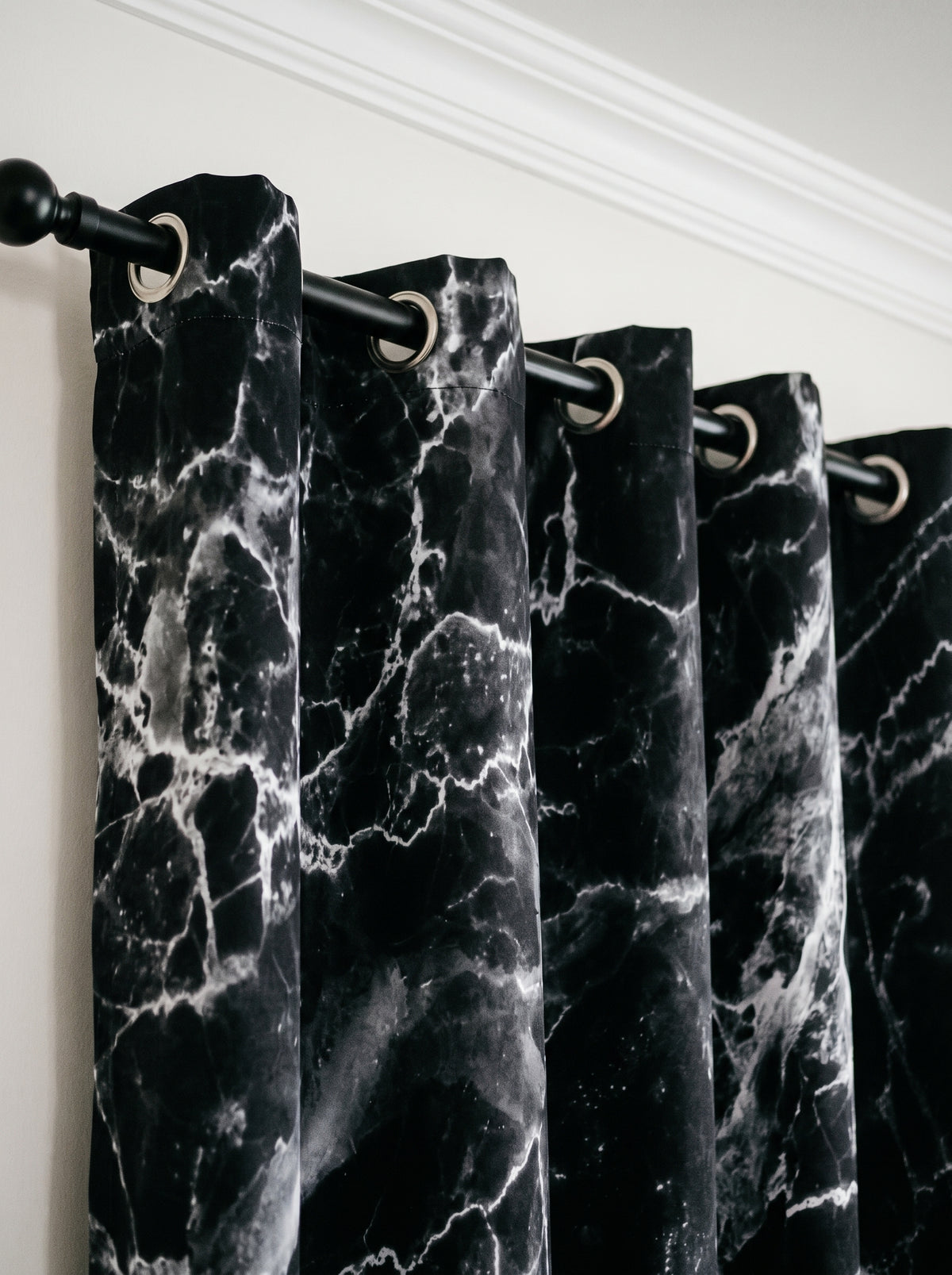 Œillets métalliques du rideau effet marbre noir enfilés sur une tringle