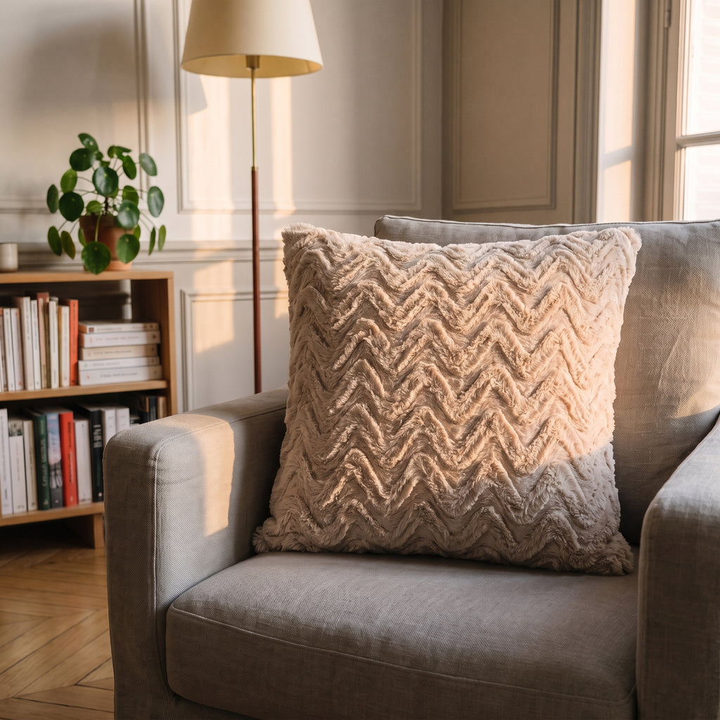 Coussin en coton beige à relief ondulé, vu de près sur un fauteuil de lecture