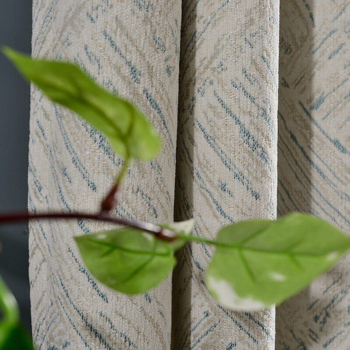 Détail du motif bleu discret sur le fond écru du rideau en chenille