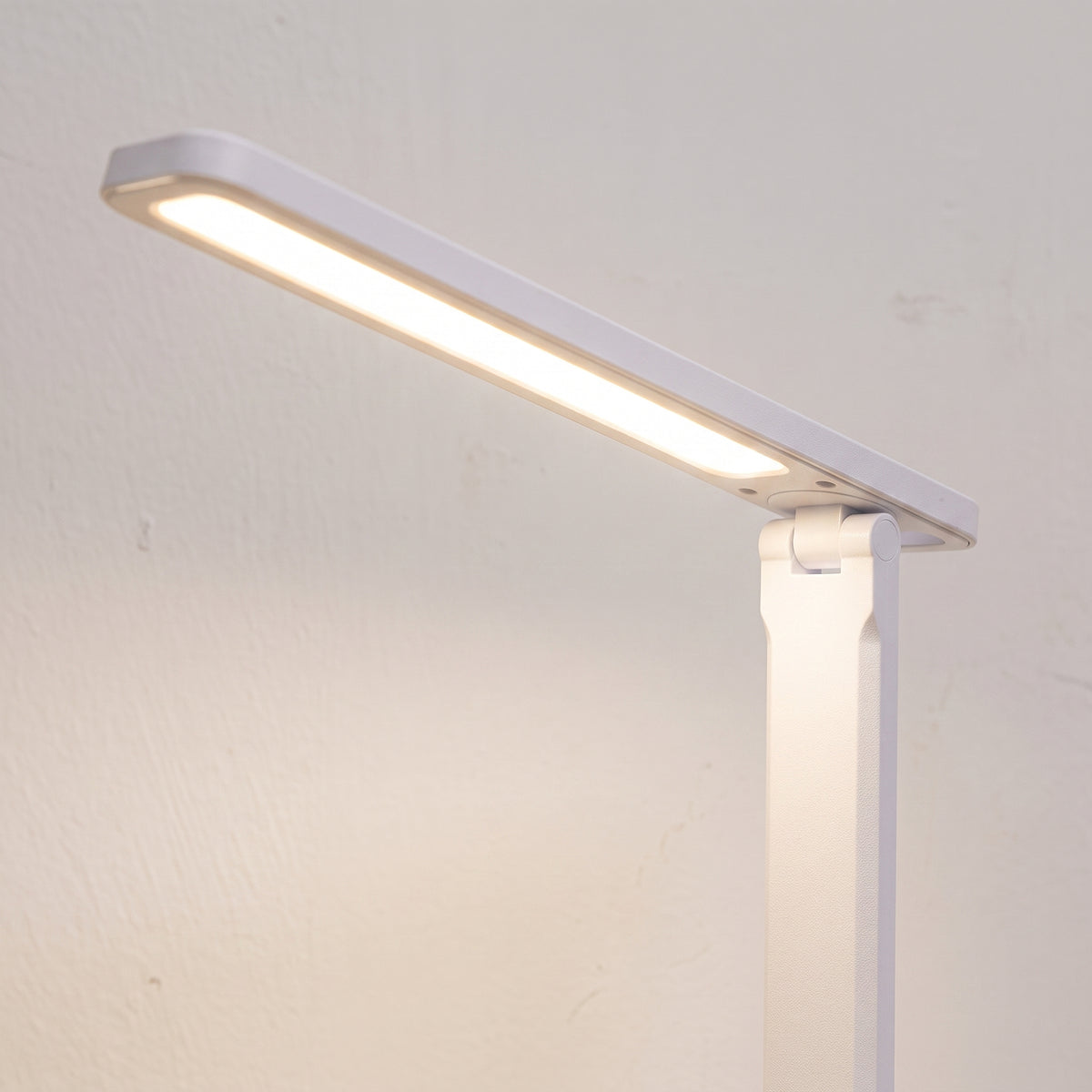 Détail de la tête allumée et de l’articulation de la lampe de bureau LED