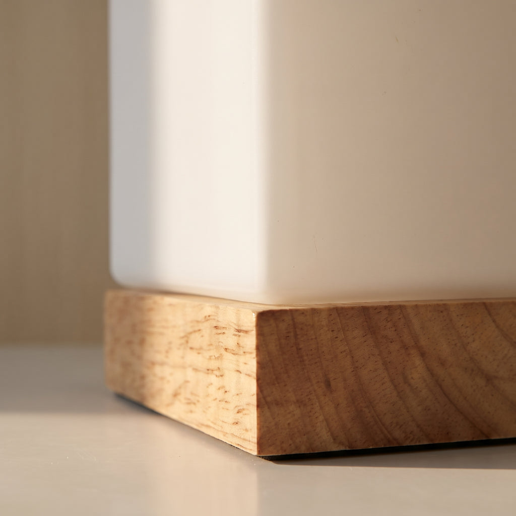 Détail du socle en bois clair et du bas de l'abat-jour blanc