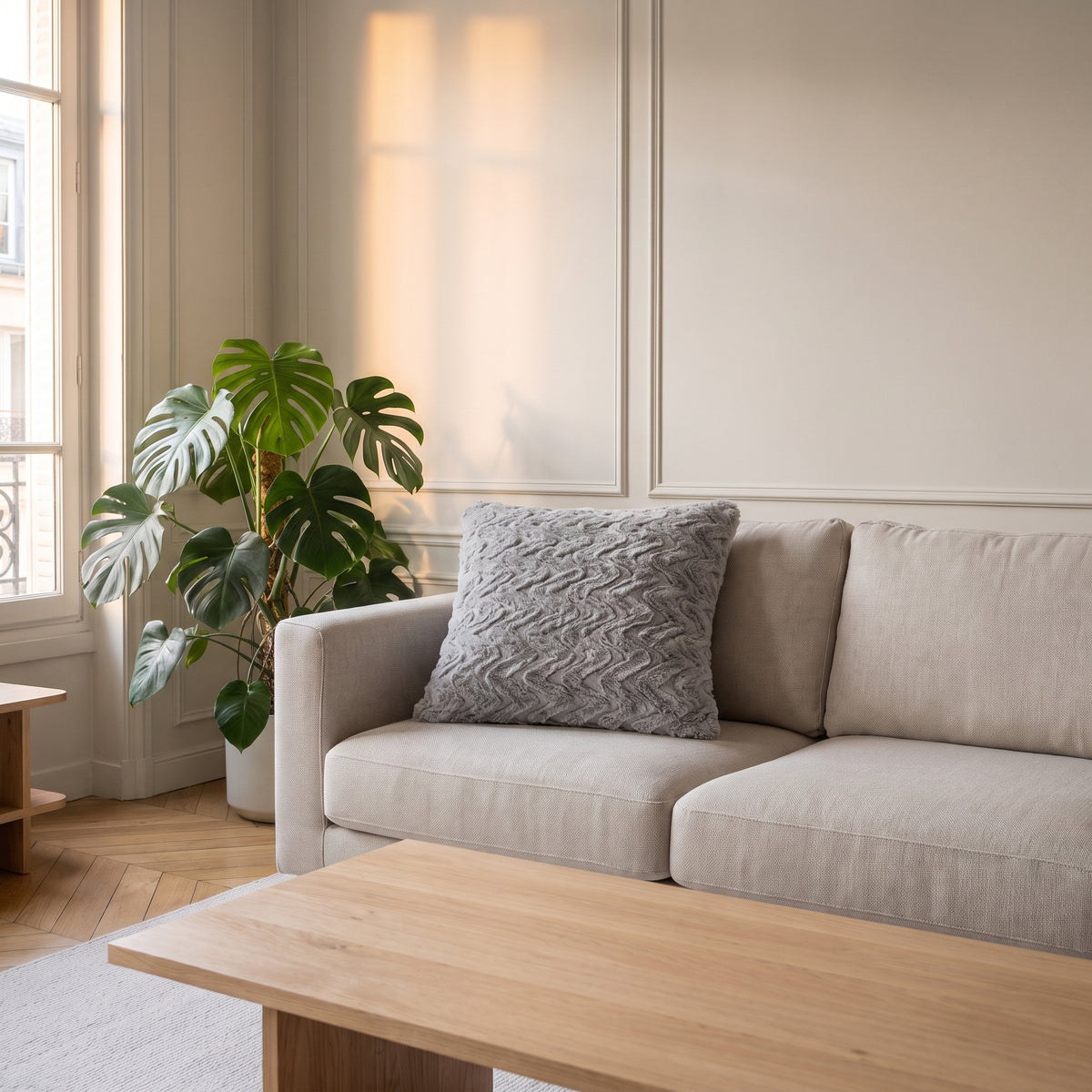 Coussin en coton gris à relief ondulé posé sur un canapé clair