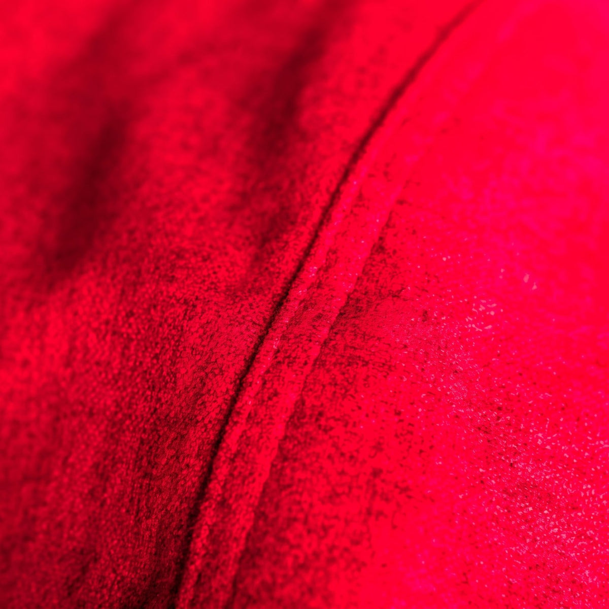 Gros plan sur la microfibre suédine rouge du pouf et sa couture