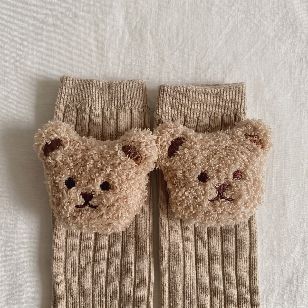 Les deux têtes d'ourson en peluche cousues sur le bord côtelé des chaussettes