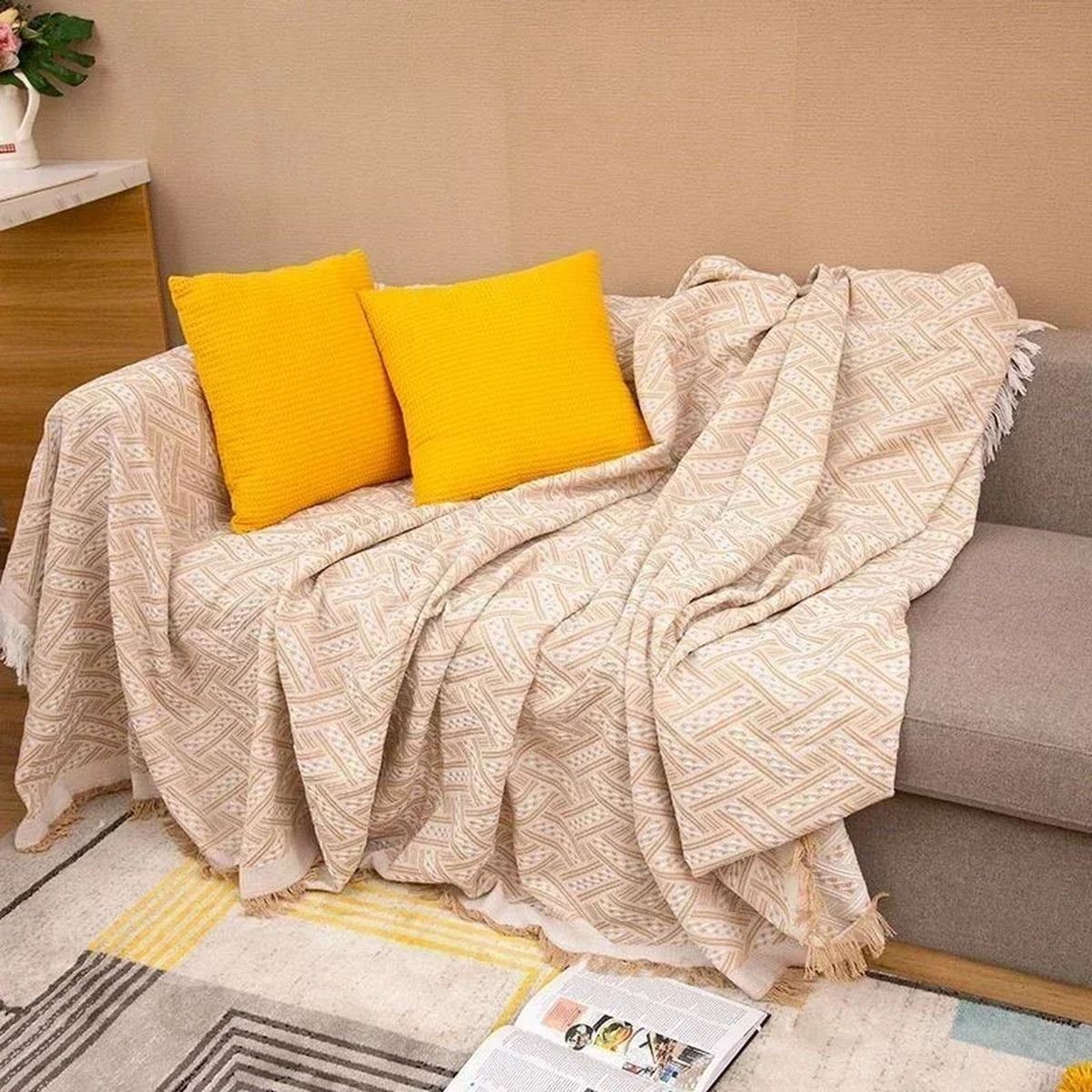 Plaid tricoté beige à franges présenté sur un canapé