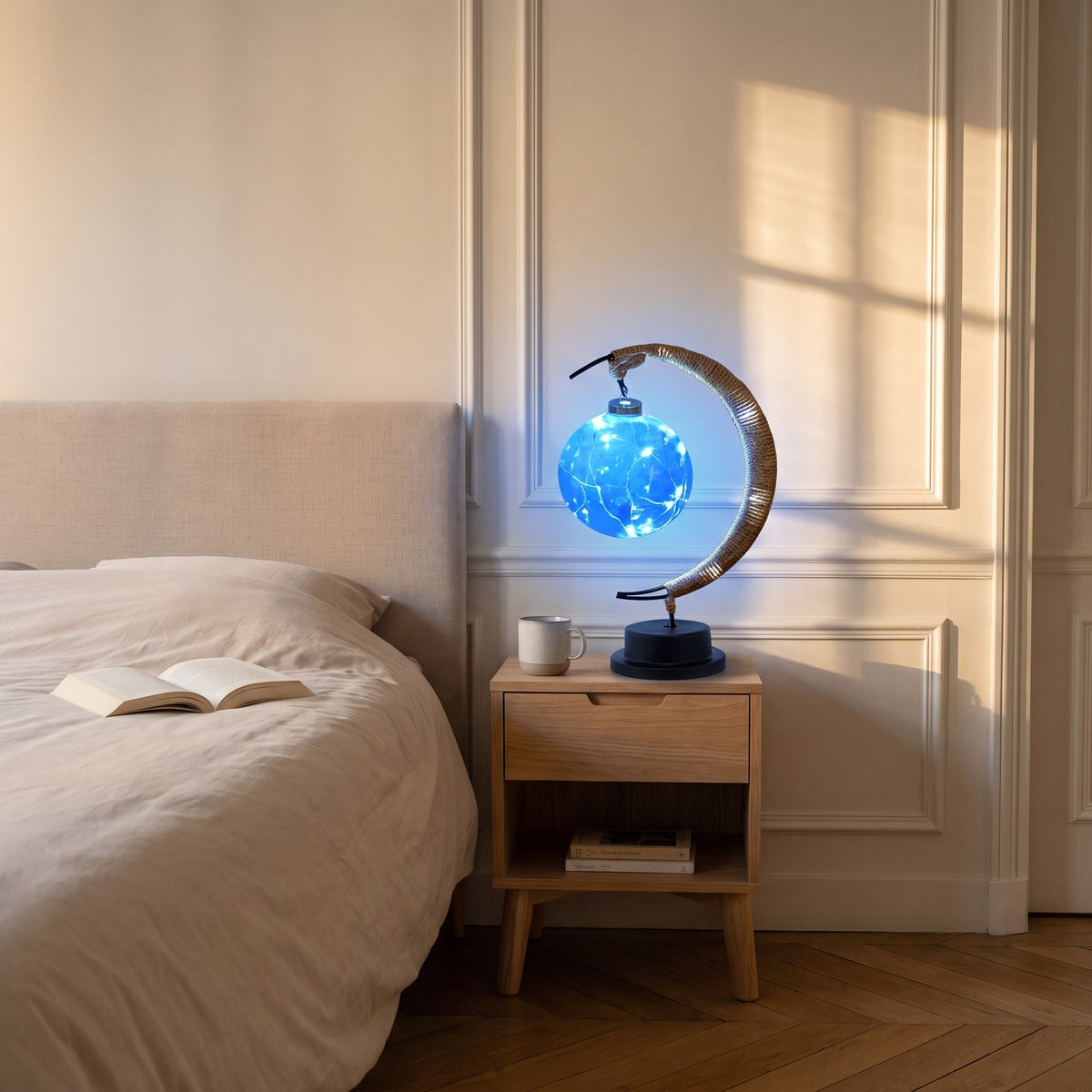 Lampe croissant de lune allumée en bleu sur la table de chevet.