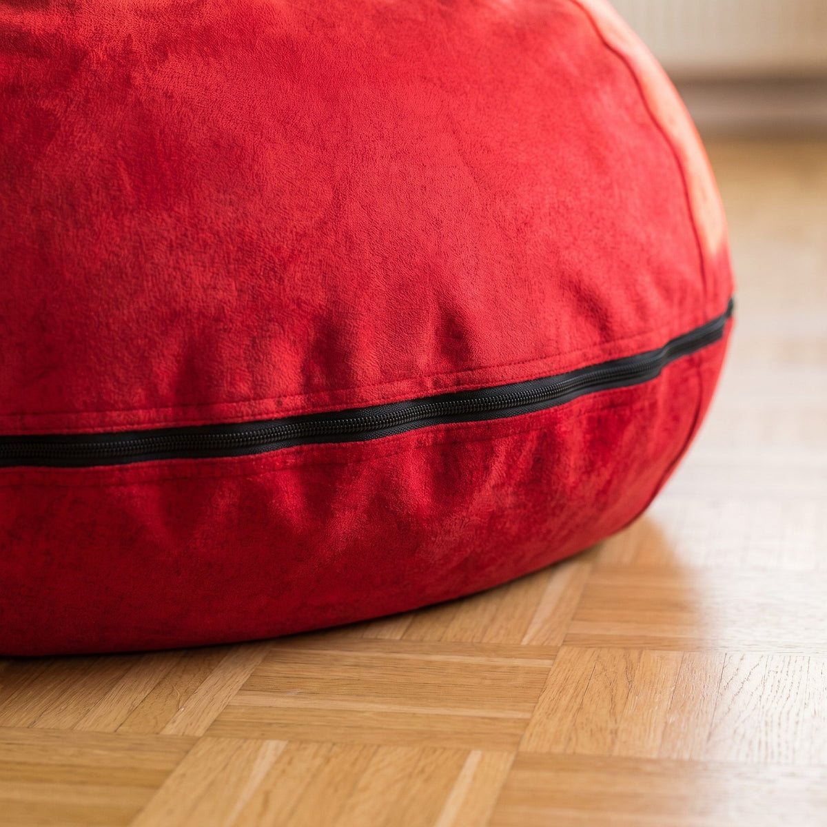 Bas du pouf rouge et la fermeture éclair noire qui court le long de la couture