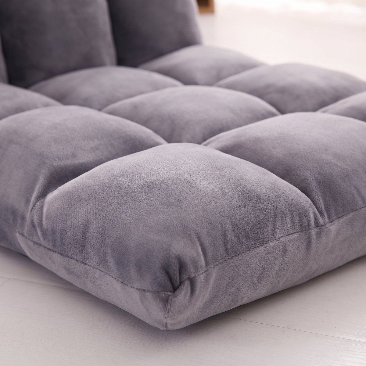 Matelassage en carrés piqués de l'assise d'un fauteuil de sol gris