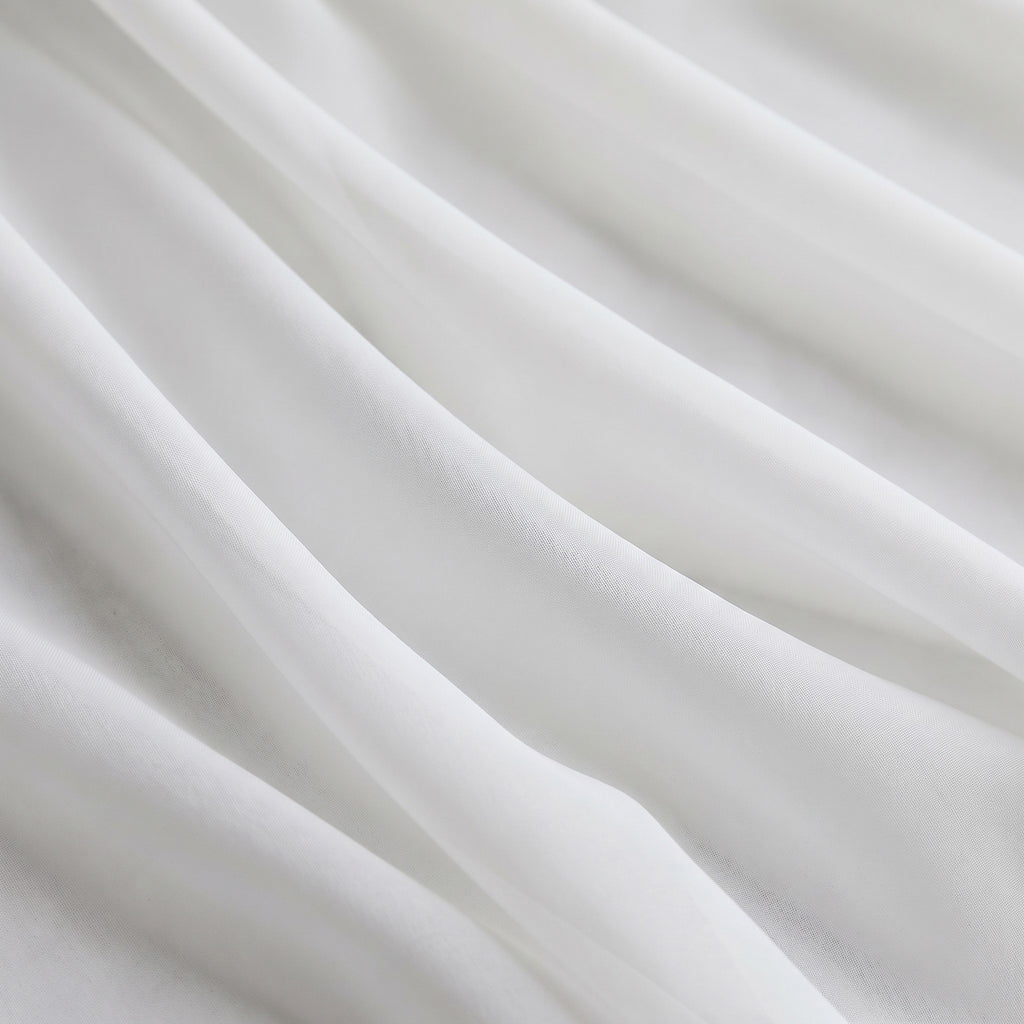 Gros plan sur le tulle blanc drapé en plis souples, la trame fine du voile est visible