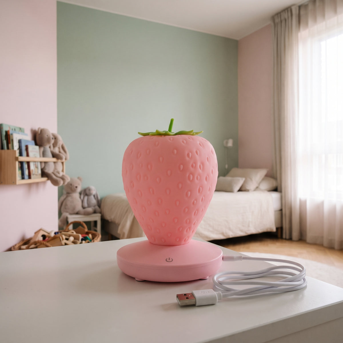 Veilleuse fraise rose posée avec son câble USB de recharge
