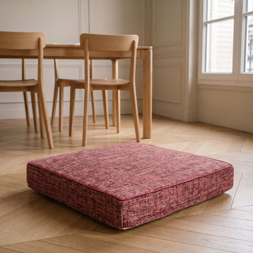 Coussin de sol rouge brique posé sous une table de salle à manger