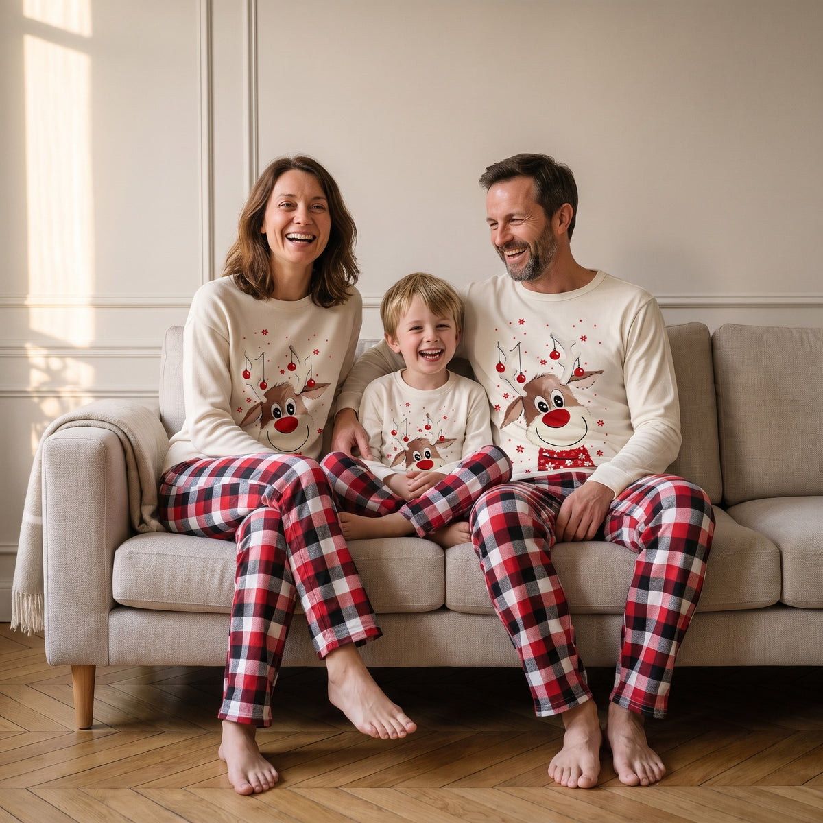 Famille réunie sur le canapé en pyjamas de Noël renne et carreaux assortis