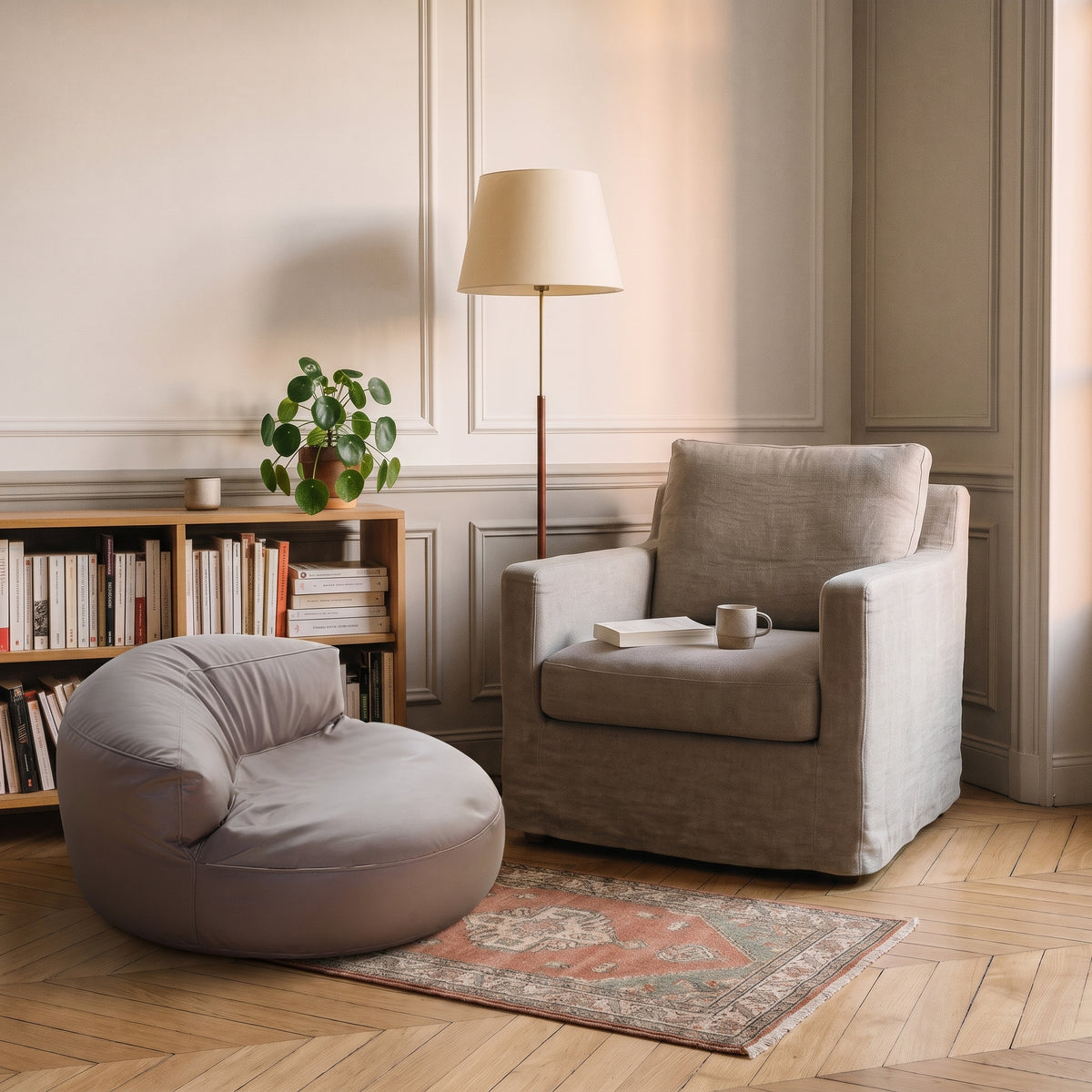 Pouf fauteuil taupe posé dans un coin lecture, à côté d'un fauteuil