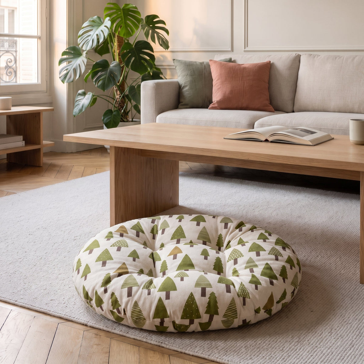 Coussin de sol rond imprimé sapins verts sur fond écru, posé au sol dans un salon clair