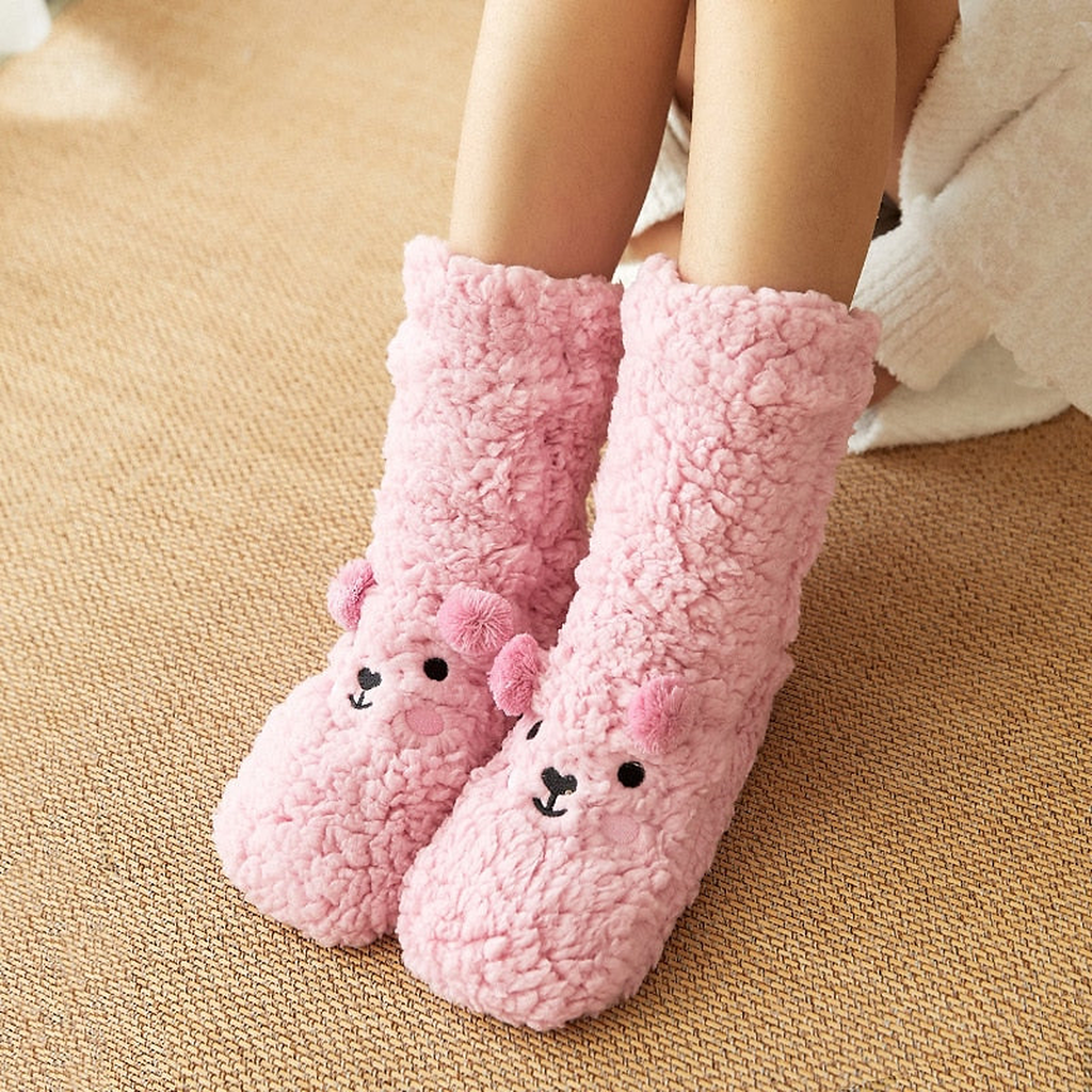 Chaussettes ourson roses portées, pieds posés sur un tapis tressé