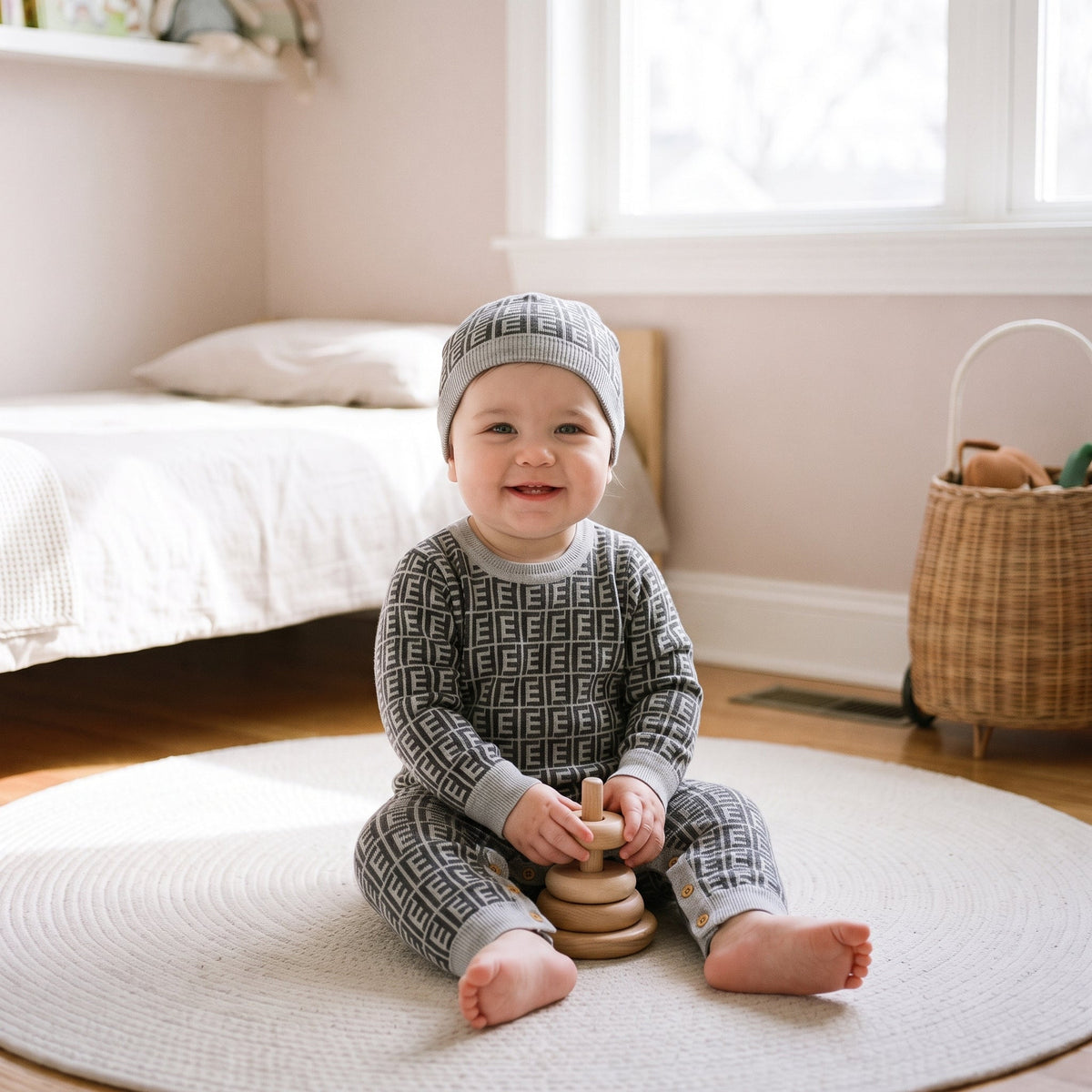 Bébé du casting jouant dans sa chambre avec la barboteuse grise et son bonnet assorti