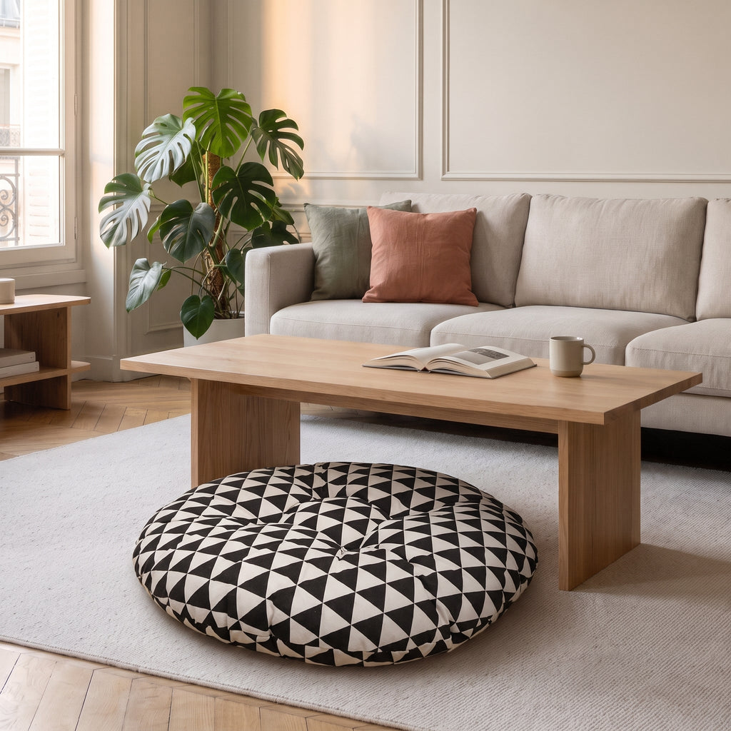 Coussin de sol rond à triangles noir et blanc, posé sur un tapis clair