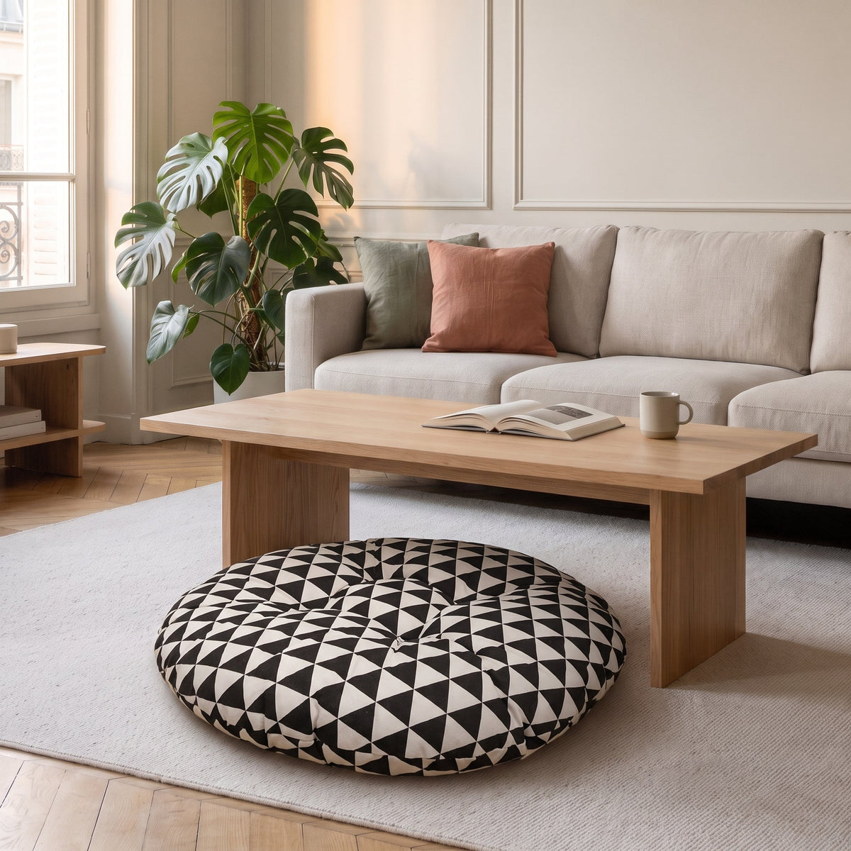 Coussin de sol rond à triangles noir et blanc, posé sur un tapis clair