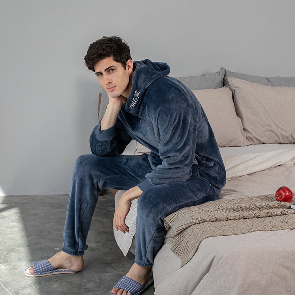 Pyjama polaire bleu marine à capuche porté par un homme assis au bord du lit