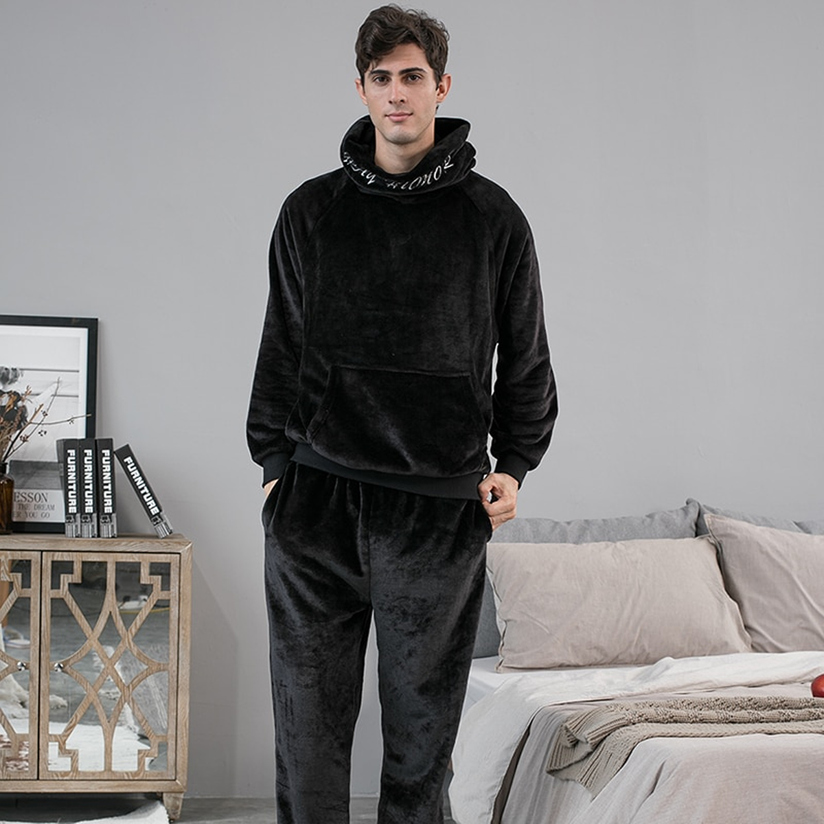 Pyjama polaire noir à capuche porté par un homme debout dans une chambre