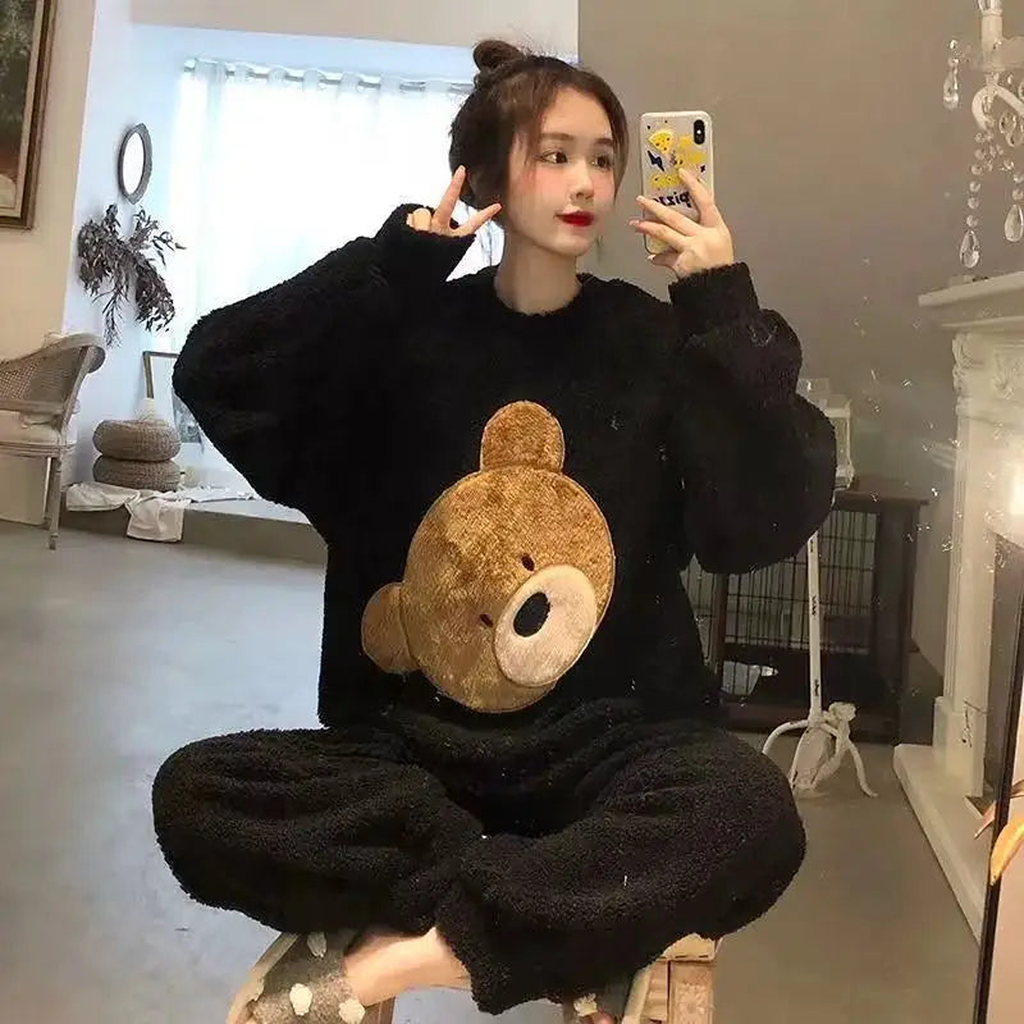 Femme en pyjama noir grand ours dans un intérieur clair