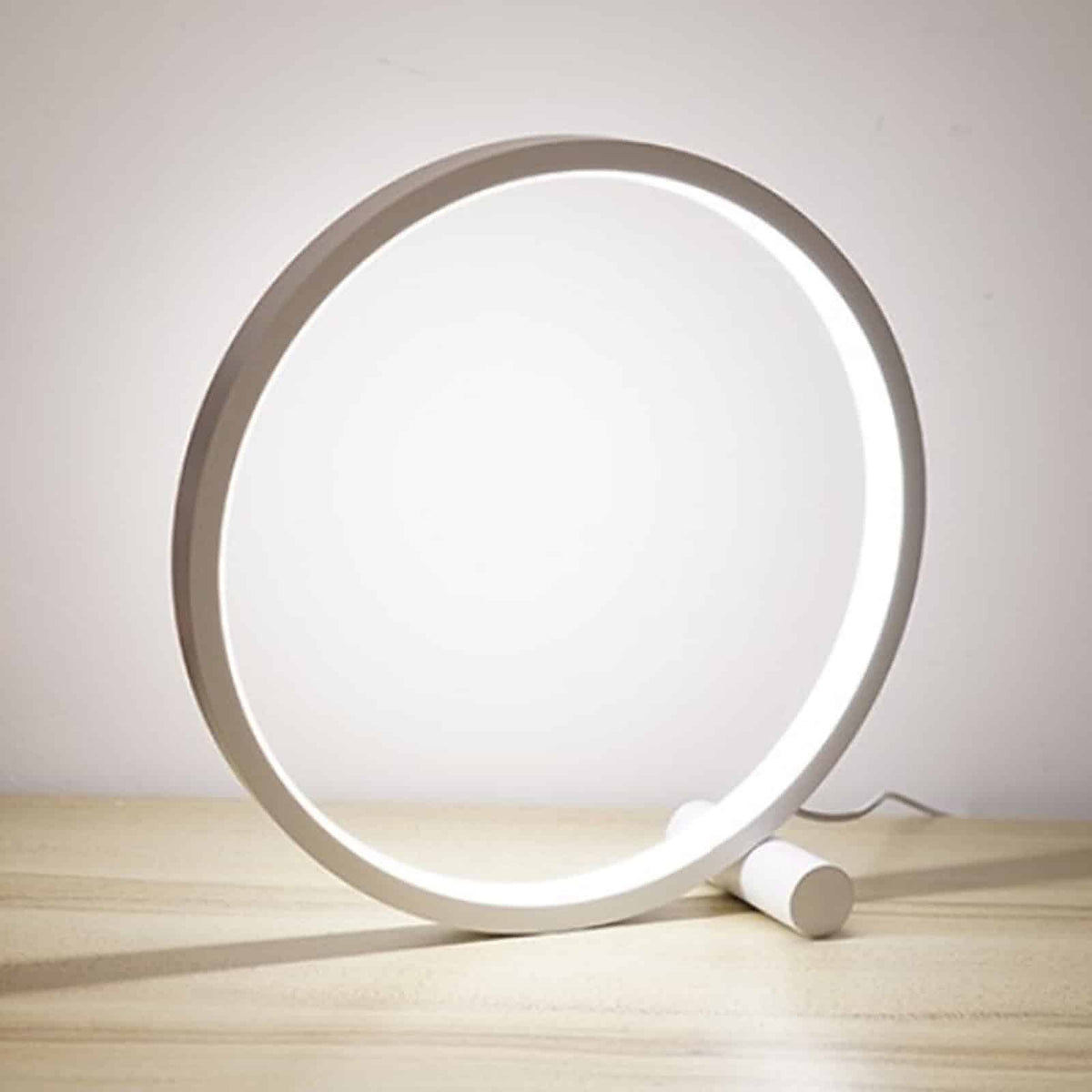 Lampe de table LED circulaire blanche allumee sur un meuble