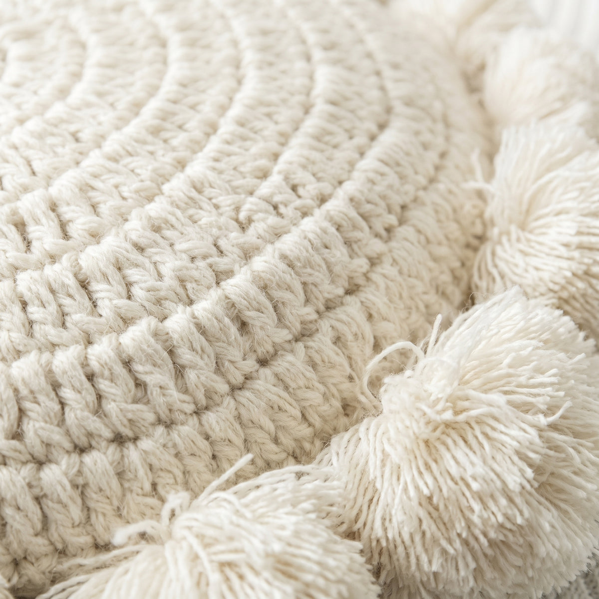 Gros plan sur la maille tricotée en spirale et les pompons du coussin Image