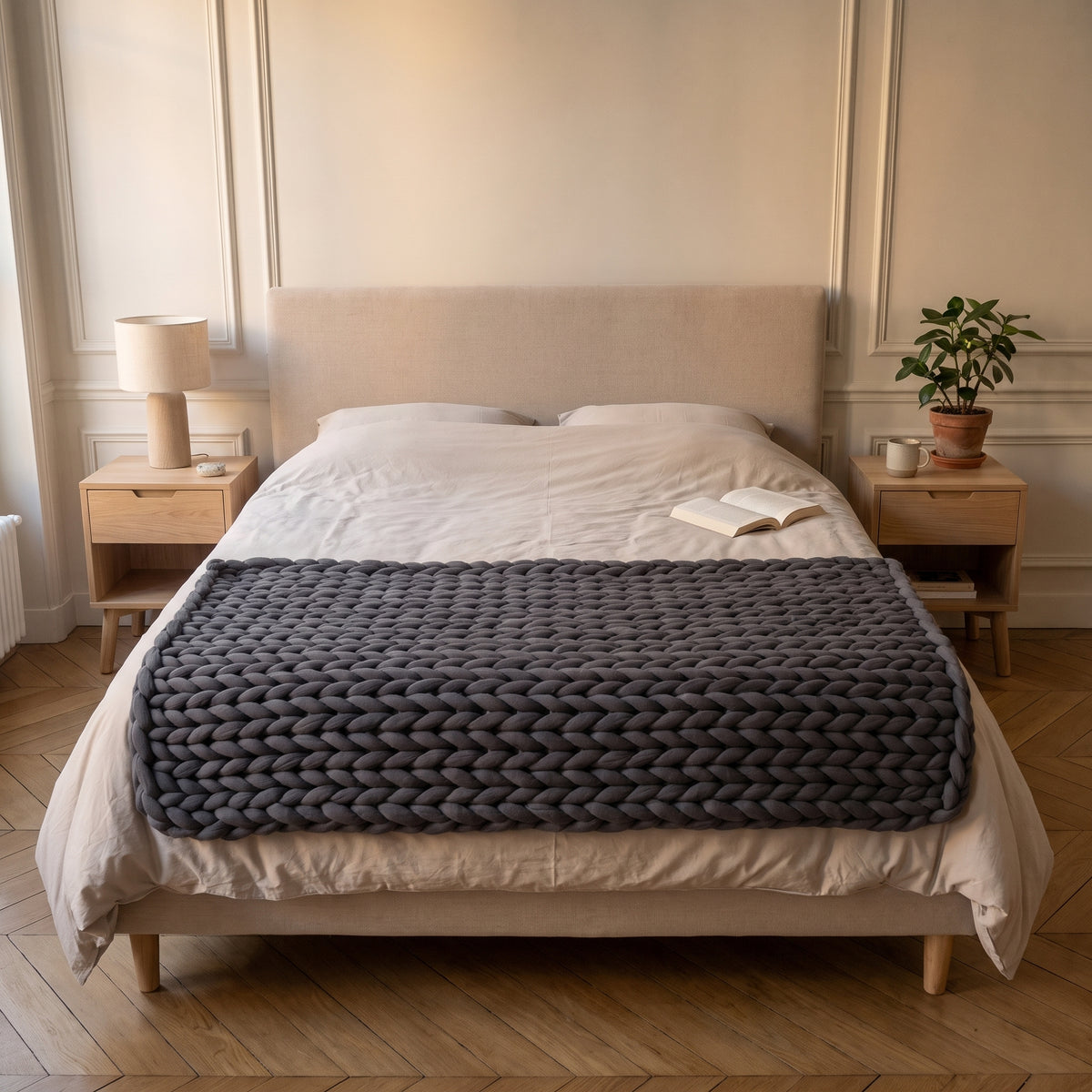 Plaid en maille géante anthracite posé en travers du pied d'un lit