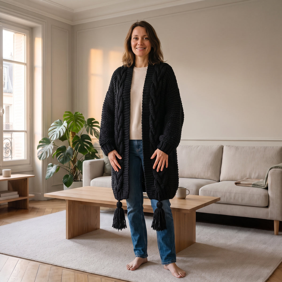Gilet long en grosse maille torsadée, coloris Noir, porté dans un salon