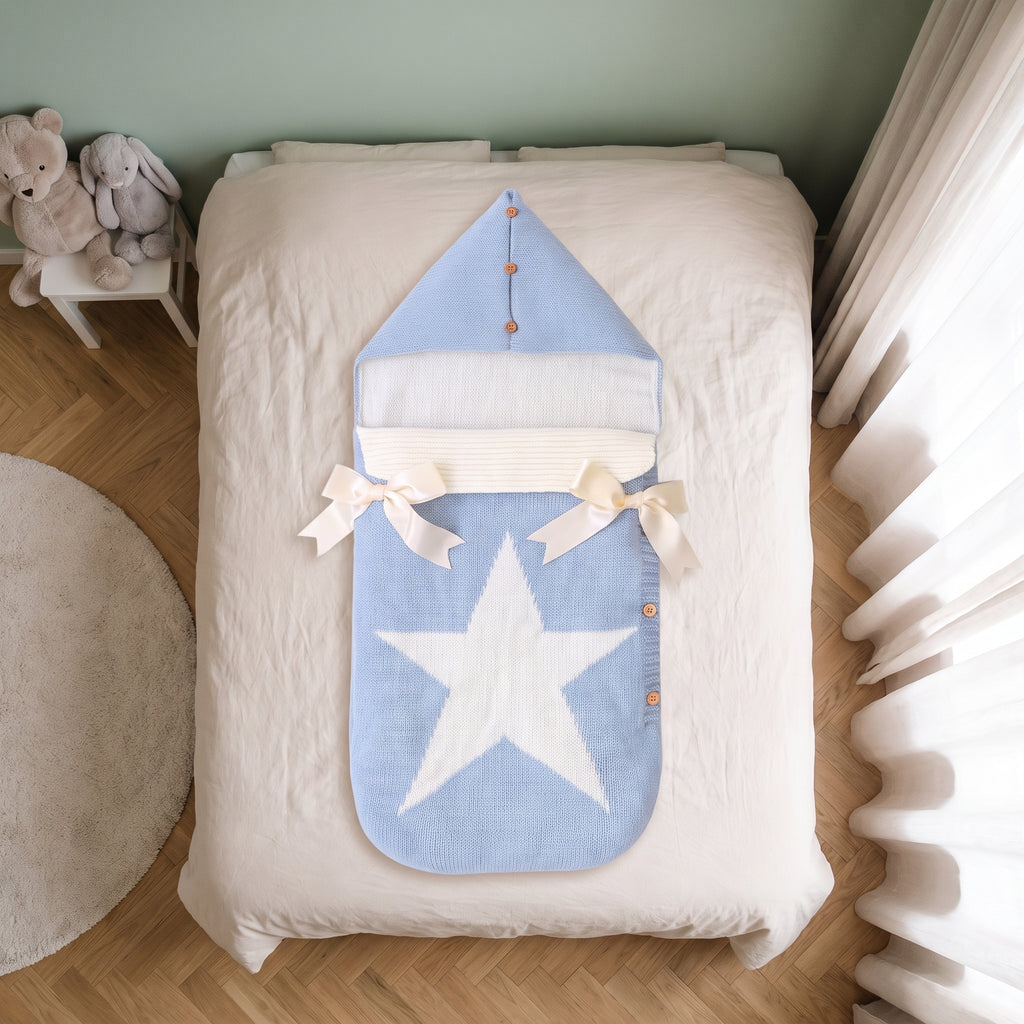 Gigoteuse bébé bleu ciel à capuche, posée sur le lit d'une chambre d'enfant