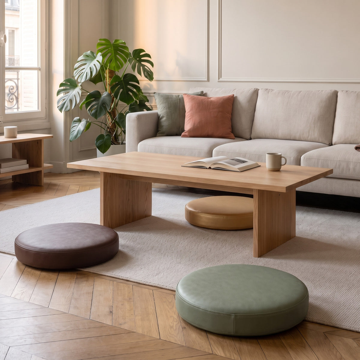 Trois coussins de sol ronds posés au sol autour d'une table basse en bois, camel, taupe et gris sauge, salon haussmannien