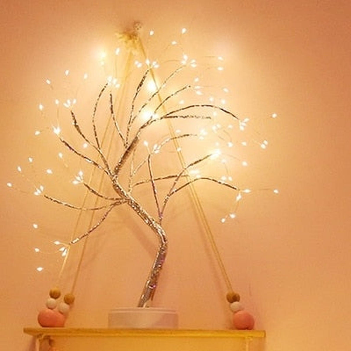 Arbre lumineux en fil de cuivre sur une étagère murale